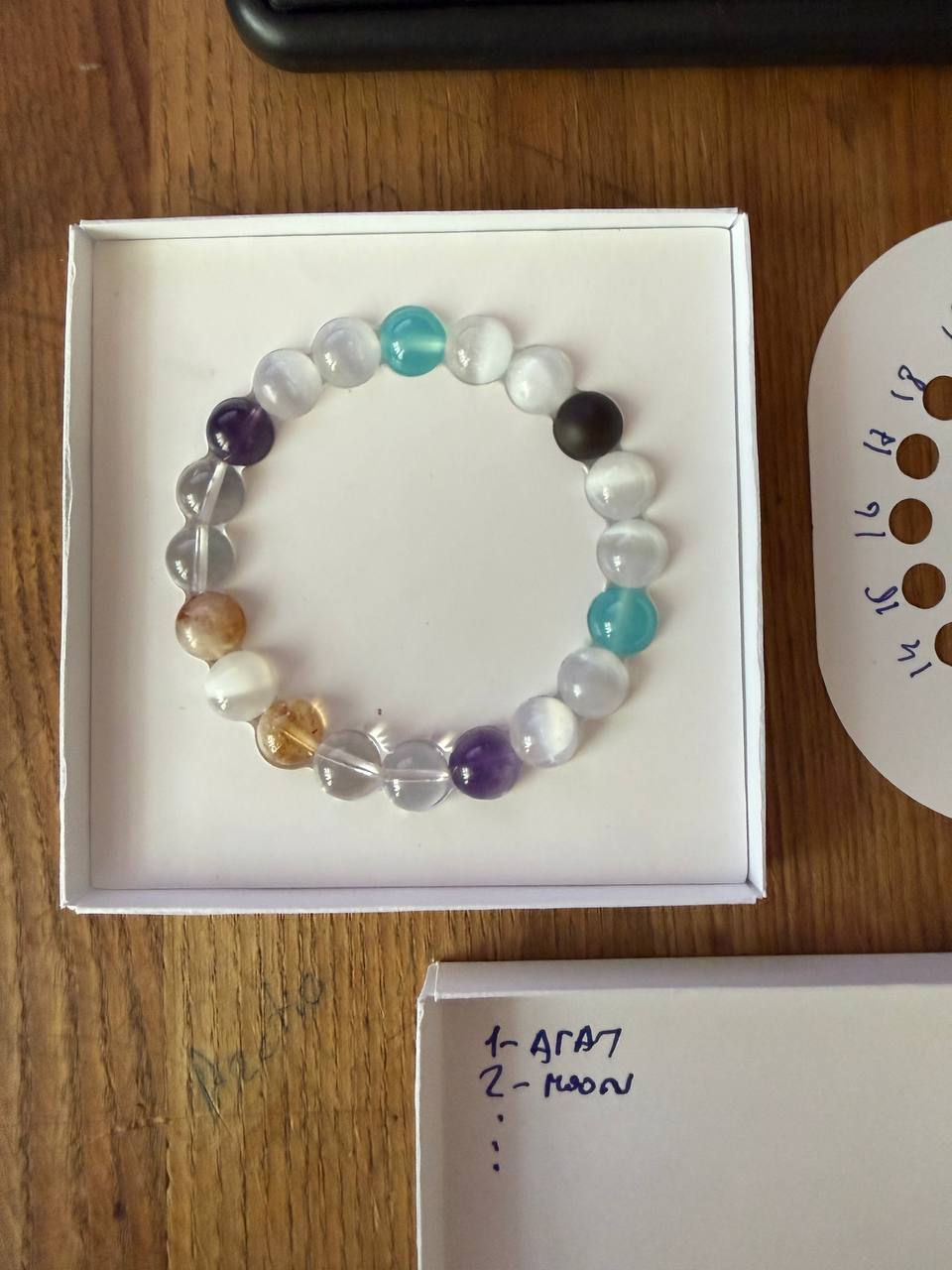 Our first bracelet: black agate, pale and transparent stones, amethyst and blue beads, arranged in its handmade box